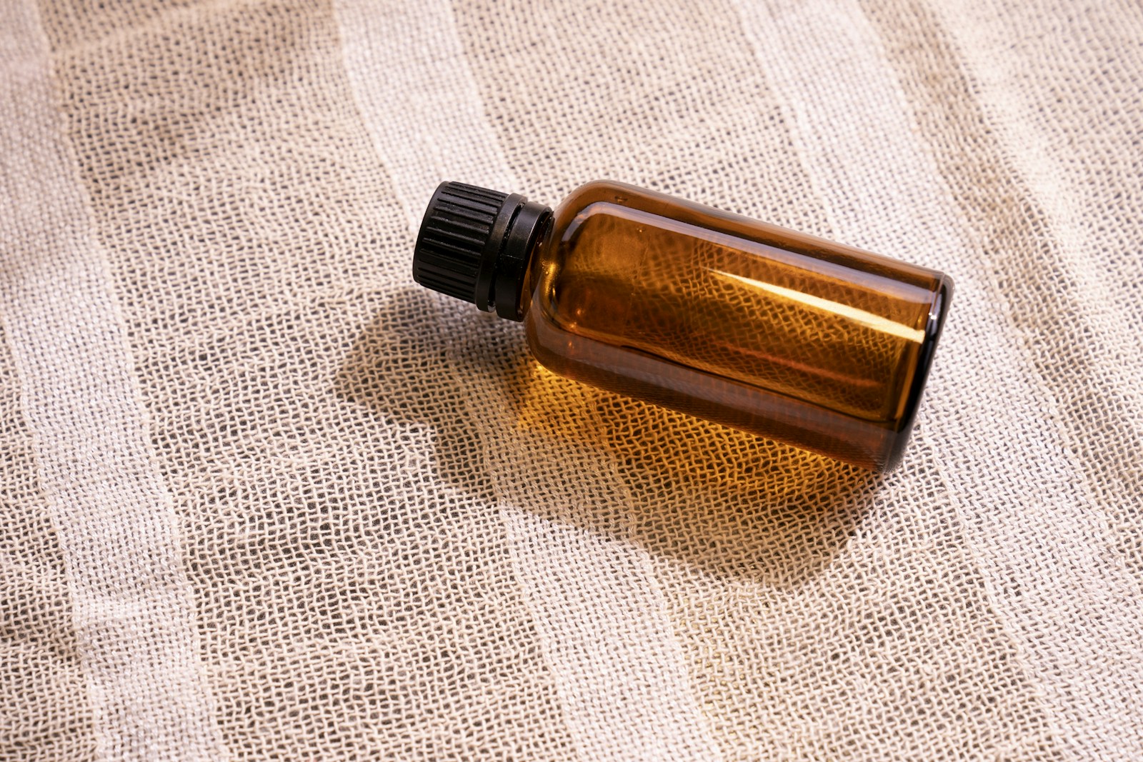 Unbranded amber glass bottle on linen, stock photograph
